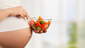 Donna incinta con una ciotola di verdure fresche